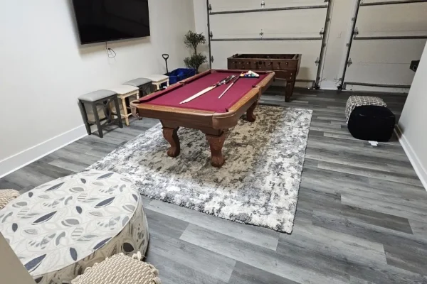 Finished garage conversion with gray plank flooring and game room